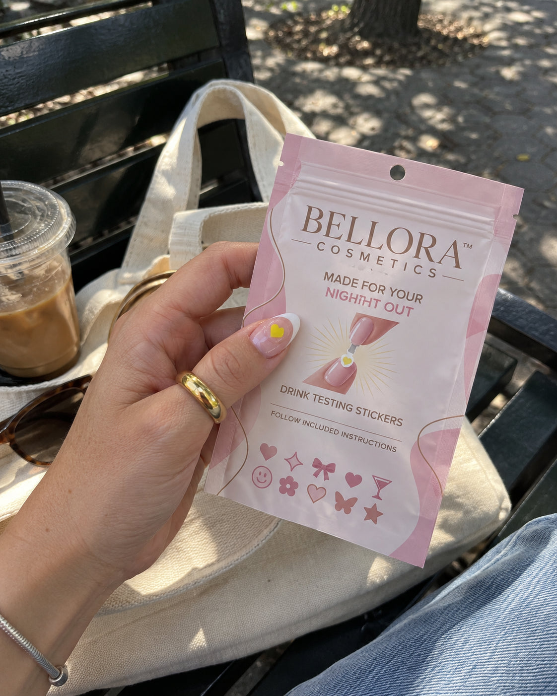 Adult hand holding Bellora over a canvas bag beside an iced drink